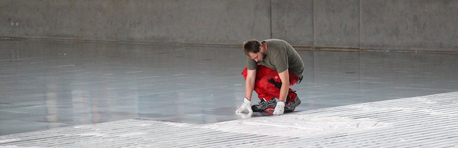 Partner und Hersteller von Fußbodenheizungen beim Einbau einer Fußbodenheizung in einer großen Halle