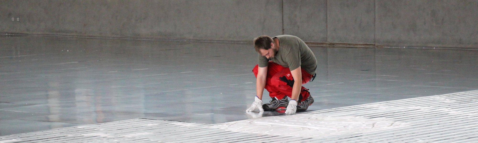 Partner und Hersteller von Fußbodenheizungen beim Einbau einer Fußbodenheizung in einer großen Halle